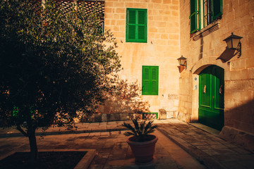Fototapeta na wymiar Beautiful Mediterranean House in Mdina, Malta. Sunset sky, Green windows and yellow wall