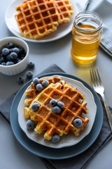 Belgian waffles with blueberries and honey on gray wooden background. Homemade healthy breakfast. Selective focus