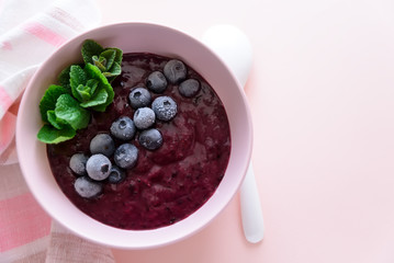 healthy berry smoothie bowl with banana on pink background. Vegetarian food or detox concept. Selective focus