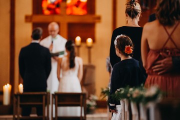 Ein kleines Mädchen beobachtet die Trauung eines Brautpaares in einer Kirche bei einer Hochzeit
