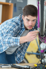 Fototapeta na wymiar male mechanic in workshop checking bicycle front brakes
