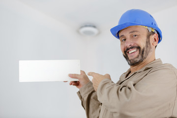 handsome repairman or builder in helmet working with board