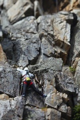 The girl climber climbs up the rocks. Tilt-Shift effect.