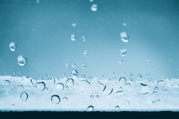 Window glass with frozen drops of rain. Atmospheric mint blue light background with raindrops....