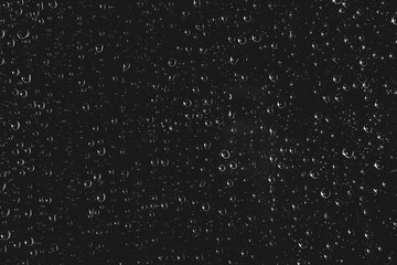 Dirty window glass with drops of rain. Atmospheric monochrome dark background with raindrops. Droplets and stains close up. Detailed transparent texture in macro with copy space. Night rainy weather.