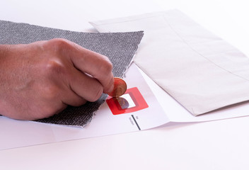 Eine Hand rubbelt mit einer Münze den PIN Code frei