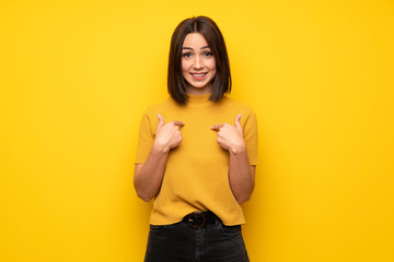 Young woman over yellow wall with surprise facial expression