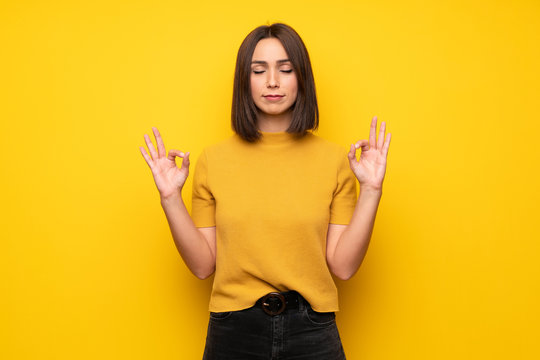 Young Woman Over Yellow Wall In Zen Pose