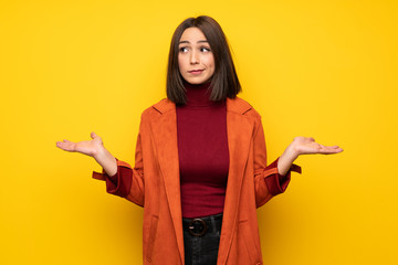 Young woman with coat having doubts while raising hands