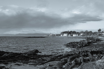 A Black & White image in the Scottish Town of largs Looking Along the Lichen Covered Rocky Foreshore.