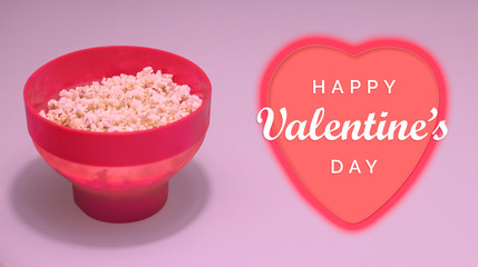 Happy Valentine's day date plan concept. Red bowl of popcorn and heart symbol.