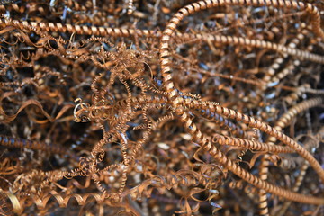 Background of tangled twisted copper colored raw industrial scrap metal spiral shavings and machine filings 