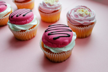 pink cream cupcakes and macaroon on pink background