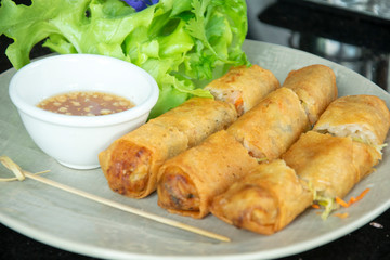 A plate of deep fried spring rolls with sweet chili dip sauce.