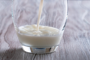 Pouring fresh milk into glass close up.