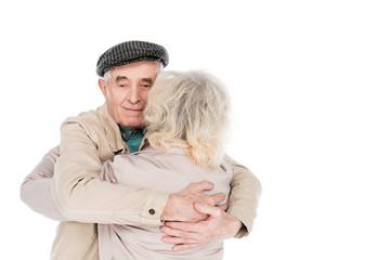cheerful retired man hugging wife isolated on white