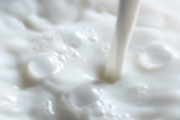 Pouring fresh milk into glass close up.