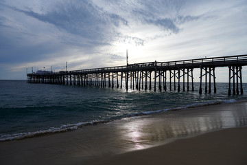 The pier at NEwport Beach in California with silhouettes of people enjoying their time at the beach
