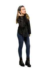 A full-length shot of a Teenager girl with leather jacket listening to something by putting hand on the ear on isolated white background