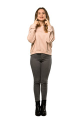 Fototapeta premium A full-length shot of a Teenager girl with pink sweater smiling with a happy and pleasant expression over isolated white background