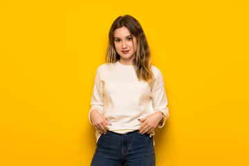 Teenager girl over yellow wall posing and laughing looking to the front