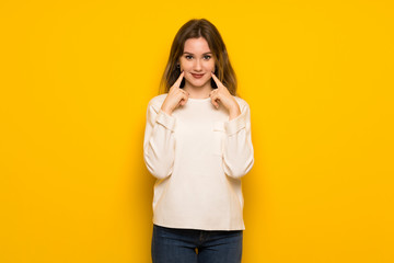 Teenager girl over yellow wall smiling with a happy and pleasant expression