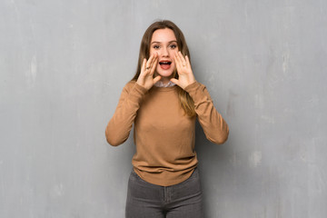 Teenager girl over textured wall shouting and announcing something