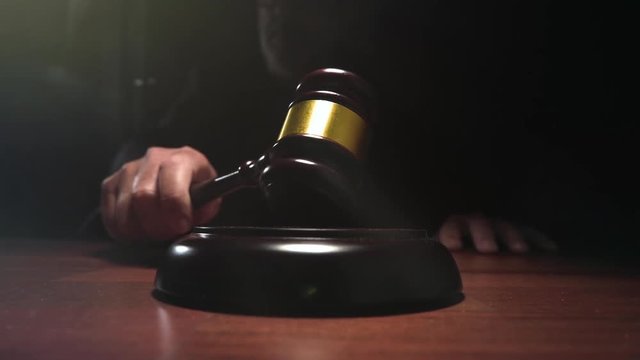 Judge hitting Gavel off a block in courtroom, dark background slow motion shot 