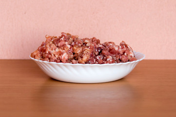 Minced pork in a white plate. Located on the kitchen table.