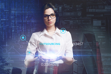 The concept of business, technology, the Internet and the network. A young entrepreneur working on a virtual screen of the future and sees the inscription: Outsourcing