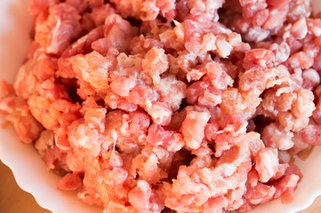 Minced pork in a white plate. Located on the kitchen table.