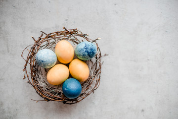  a nest and several eggs with willow sticks . Abstract grey stone background, happy easter concept