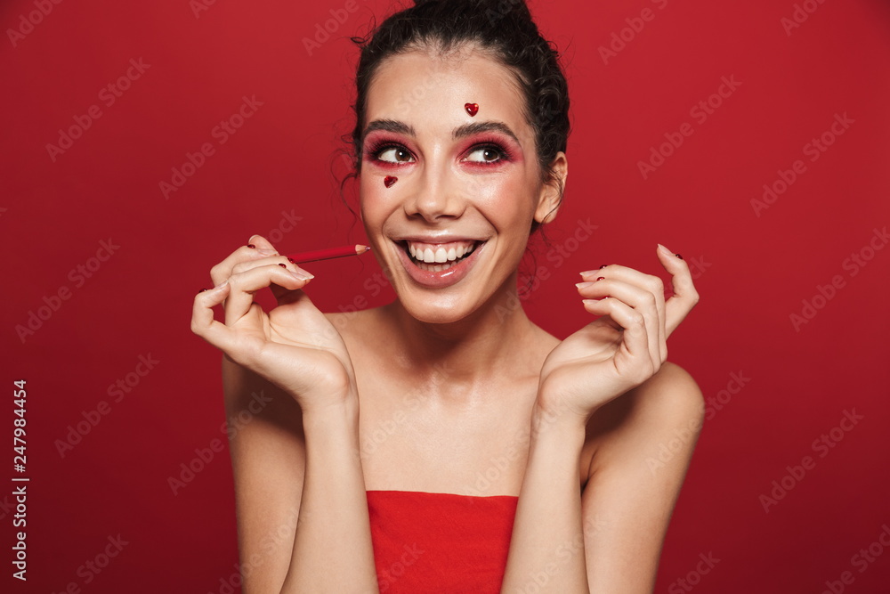 Sticker beautiful young woman with red bright makeup isolated over red wall background posing with hearts on