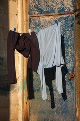 Male clothes hanging to dry outdoor of house. Rusty closed door and cement brick wall at background. 