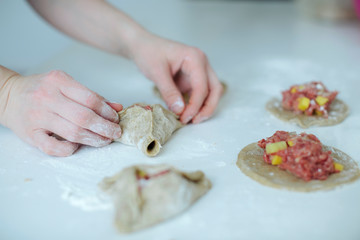 The girl carefully and gently sculpts meat pies. hands closeup on the table with flour