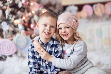 Obraz premium brother and sister 6-7-8 years old, happy children, a girl in a hat on Christmas eve, light colors near the house