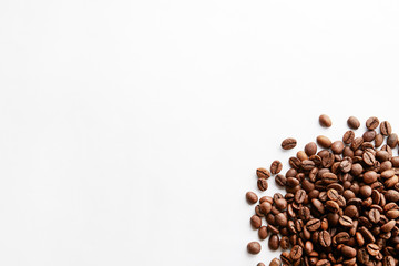 Roasted brown coffee beans scattered on white table with a lot copy space for text. Flat lay...