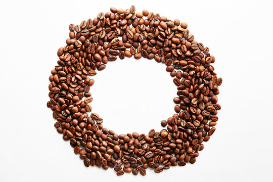 Roasted brown coffee beans scattered on white table with a lot copy space for text. Flat lay composition. Close up, top view, background.