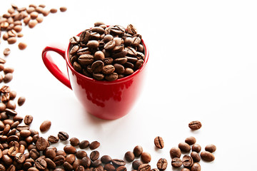 Coffee cup with roasted brown beans scattered on white table with a lot copy space for text. Flat lay composition. Close up, top view, background.