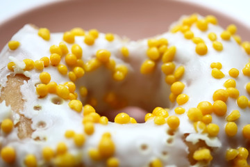 Tasty white donut with yellow round sprinkles. Background, texture. Close up. Macro