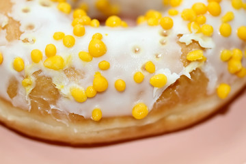 Tasty white donut with yellow round sprinkles. Background, texture. Close up. Macro