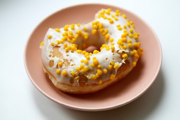 Tasty white donut with yellow round sprinkles. Background, texture. Close up. Macro