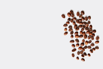 Roasted brown coffee beans scattered on white table with a lot copy space for text. Flat lay composition. Close up, top view, background.