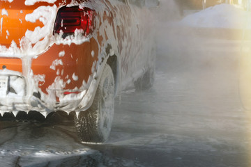 Car is cleaning with soap suds at self-service car wash. White lather on auto. Water splashes...