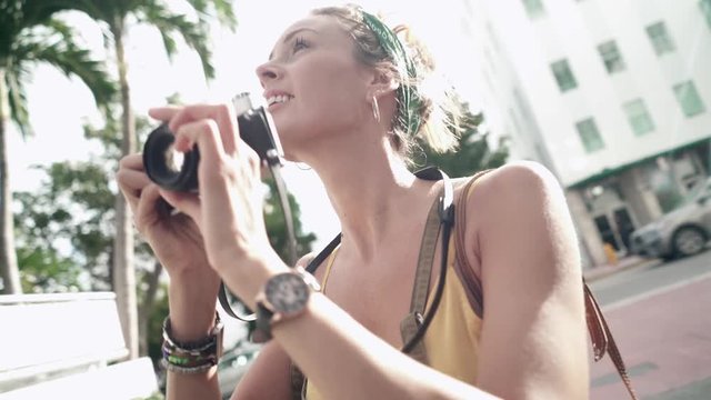 Smiling photography student taking photos in warm sunny city with vintage camera