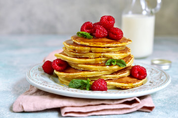 Stack of delicious homemade hot pancakes with honey and fresh raspberry.