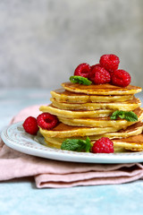 Stack of delicious homemade hot pancakes with honey and fresh raspberry.