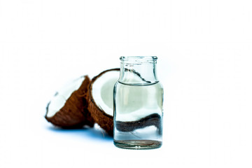 Raw organic coconut with its extracted fresh water in a white transparent glass bottle isolated on white.