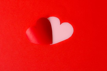 Two hearts: pink and red, together, red background, selective focus, free copy space, blurred