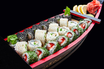 Sushi set in a wooden boat on a black background
